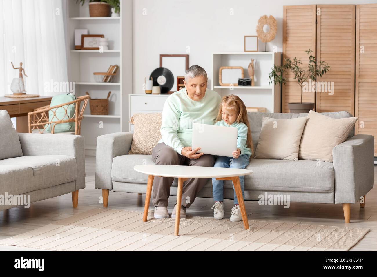 Cute little girl with her granny using laptop at home Stock Photo - Alamy
