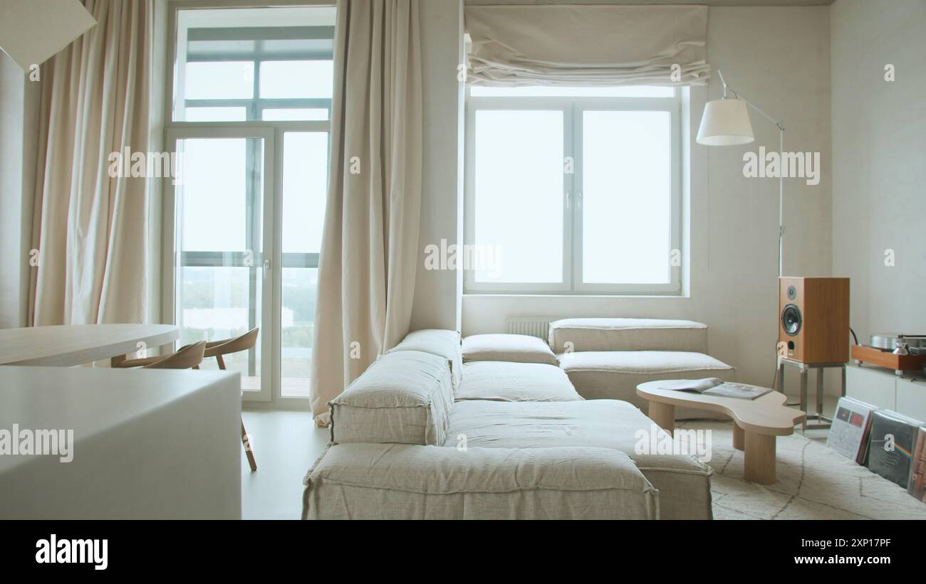 Modern interior design of open space with adjustable sofa, furniture, wooden coffee tables, patterned bedspreads, pillows, and stylish personal access Stock Photo