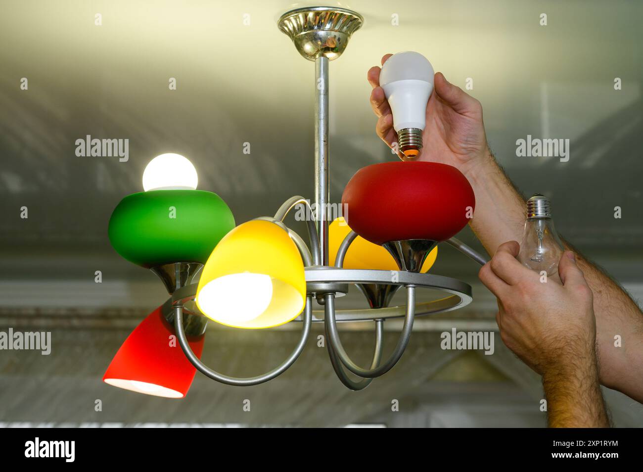 Replacing an incandescent light bulb with an LED one in a lamp Stock Photo