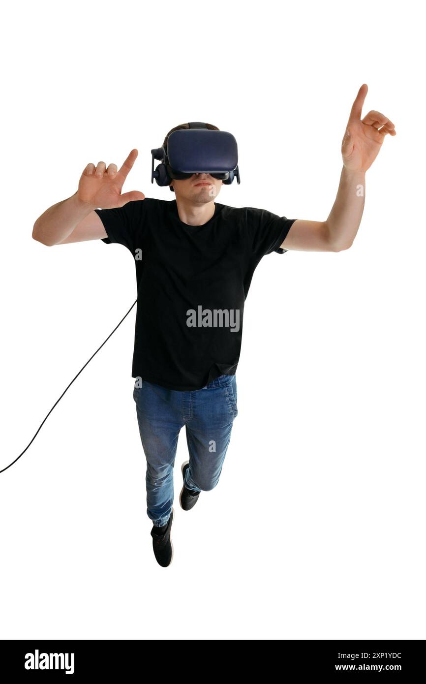 Calm young man wearing VR goggles and pointing in the air while flying on white background. 3d glasses. Innovation entertainment concept Stock Photo