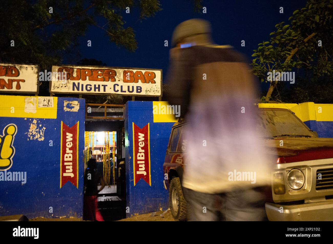 Blurred figure entering Super Bar Night Club in Gambia, depicting ...