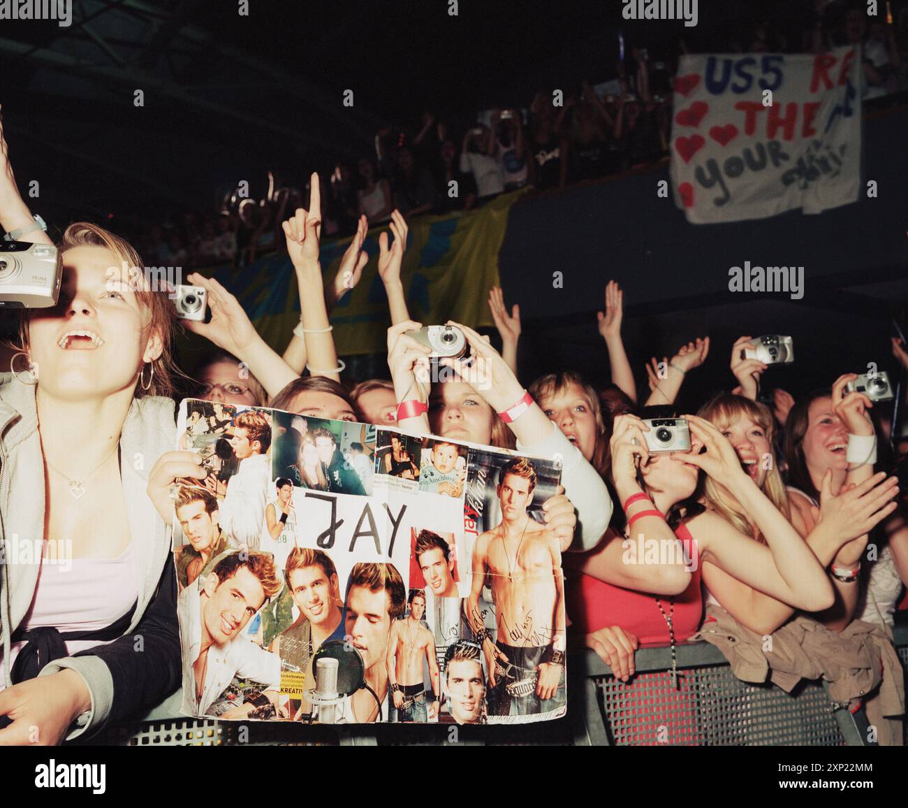 Female fans enthusiastically take pictures and hold posters at a US5 concert in Berlin, May 2006. Shows the excitement, fandom, and energy of live music events. Stock Photo