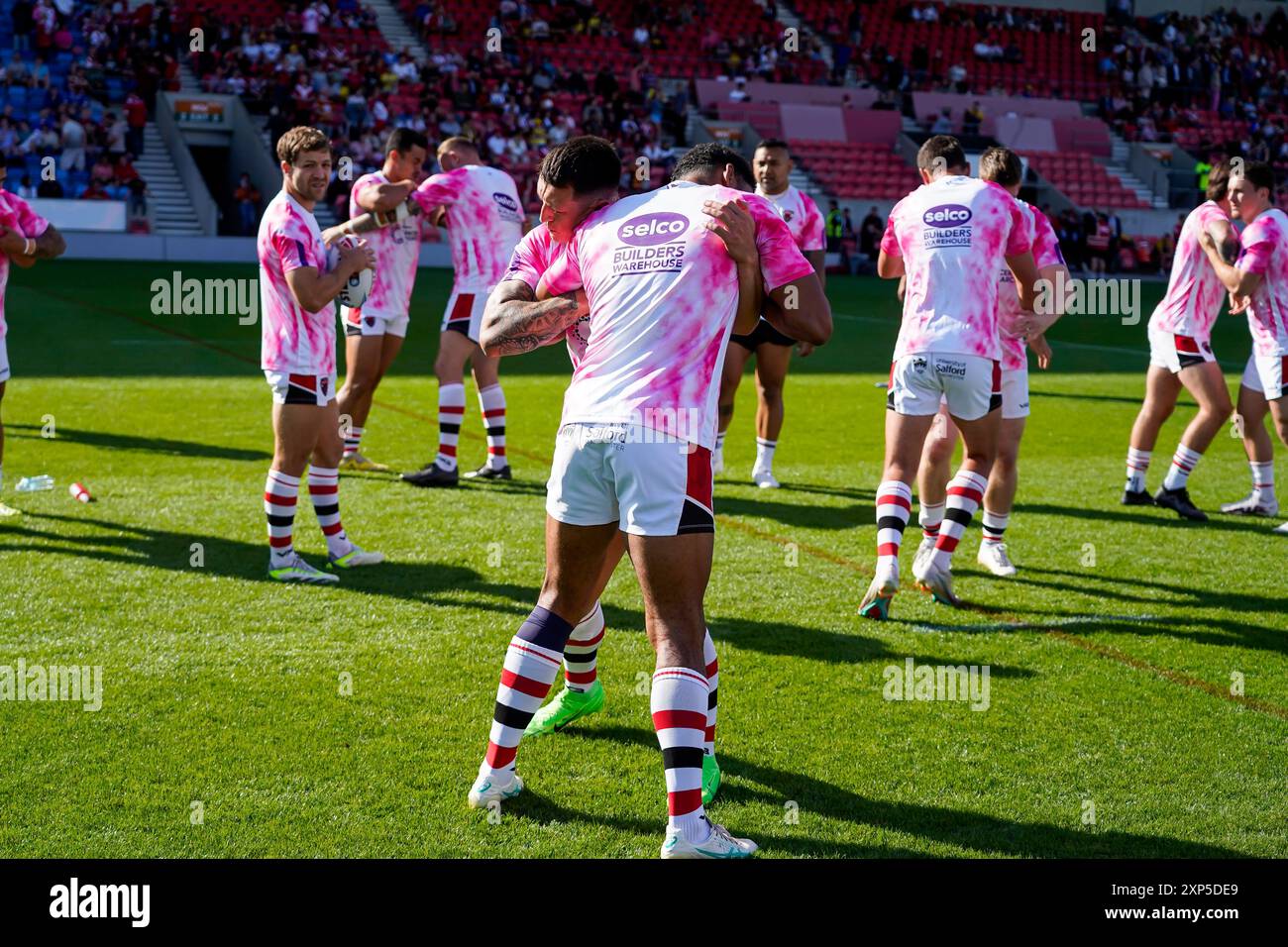 Salford, Manchester, UK. 3rd August, 2024. Super League Rugby: Salford Red Devils Vs Leeds Rhinos at Salford Community Stadium. Salford warm up in Cancer Research training tops before their game vs Leeds Rhinos. Credit James Giblin/Alamy Live News. Stock Photo