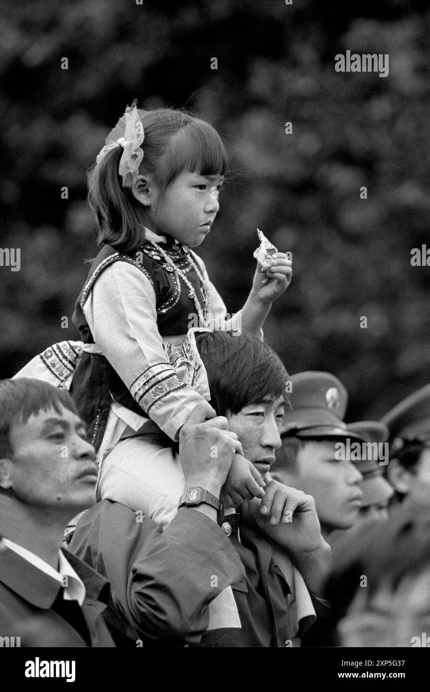 A young girl on her dads shoulders during Nation Day in Kunming China before the economic revolution- 1986 Stock Photo