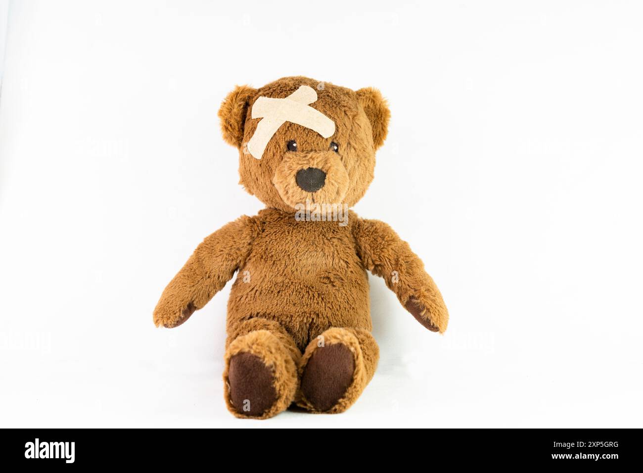 A brown teddy bear with a bandage on its head Stock Photo - Alamy