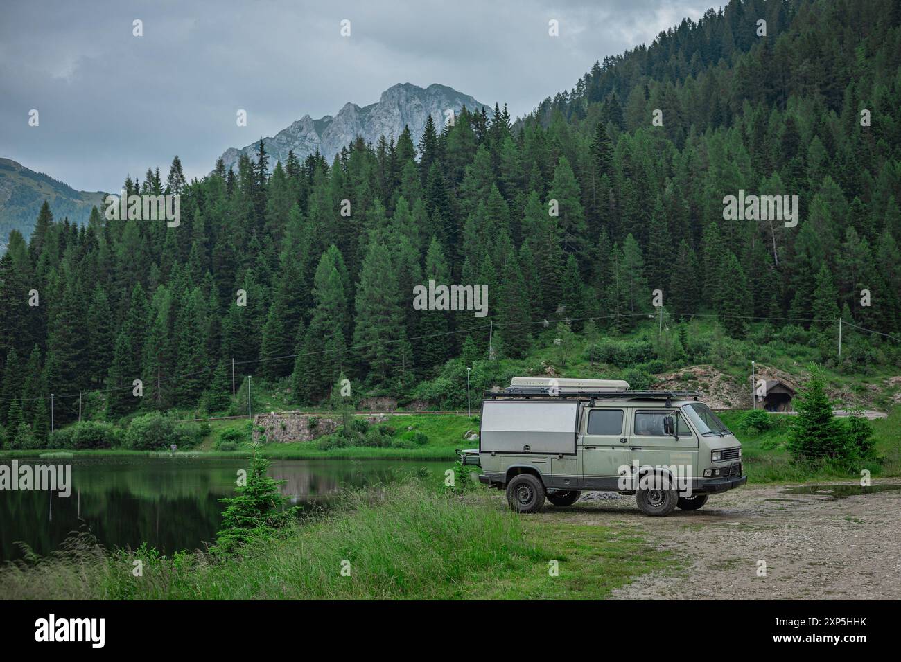 Vintage camper or campervan parked next to the pramollo lake on italian side of nassfeld pass. Cool vintage camper with majestic backdrop of mountains Stock Photo