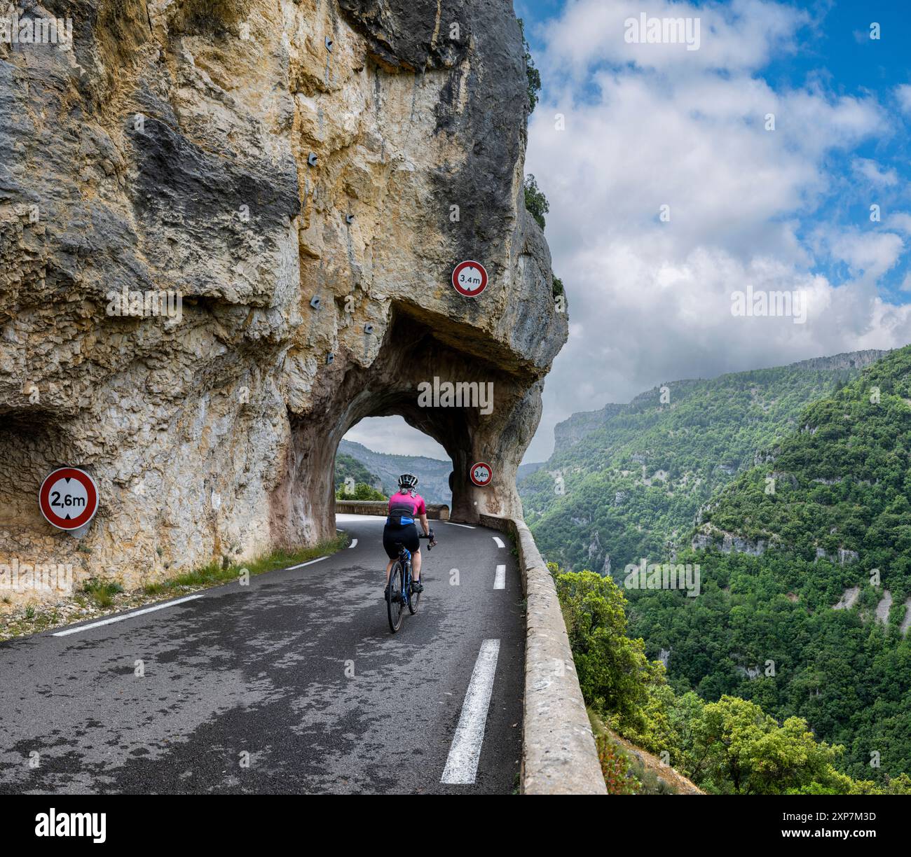Female road cyclist riding through the tunnels of the Gorges de la ...