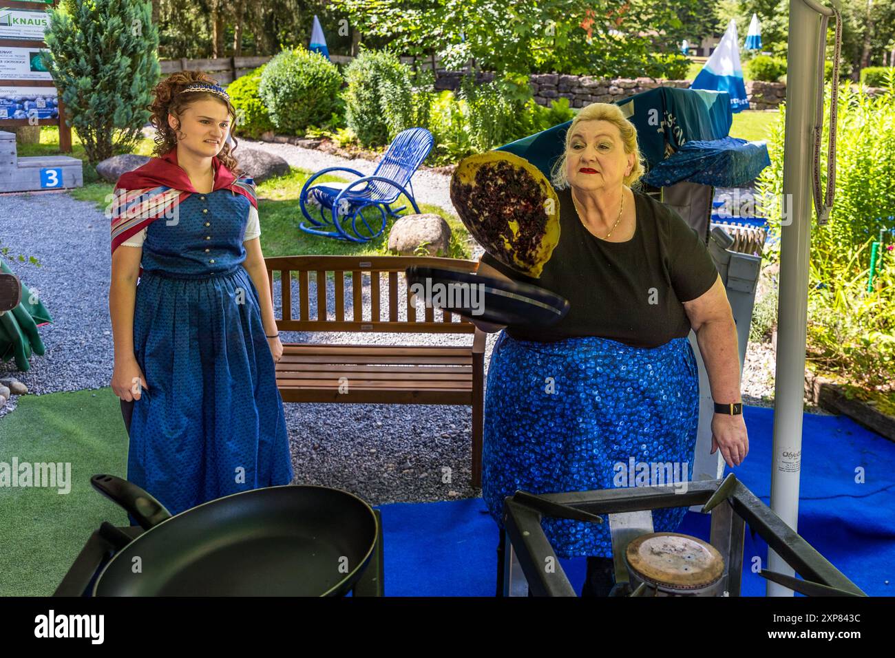 Nicoeltta Kern flips blueberry pancakes under the watchful eye of the Blueberry Queen. The beer garden at Adventure Golf in Enzklösterle is a great place to enjoy this Black Forest speciality in summer. Blueberry pancake. Wildbader Straße, Enzklösterle, Baden-Württemberg, Germany Stock Photo