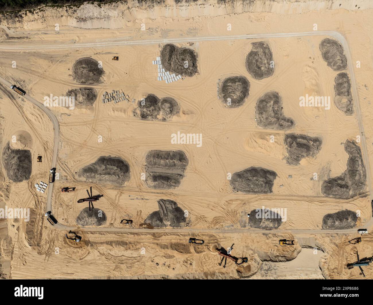 Quarrying sand. Machines and truck working on sand mine. Mining quarry open pit excavation sand mine. Aerial drone view of a sand mine in the forest. Stock Photo