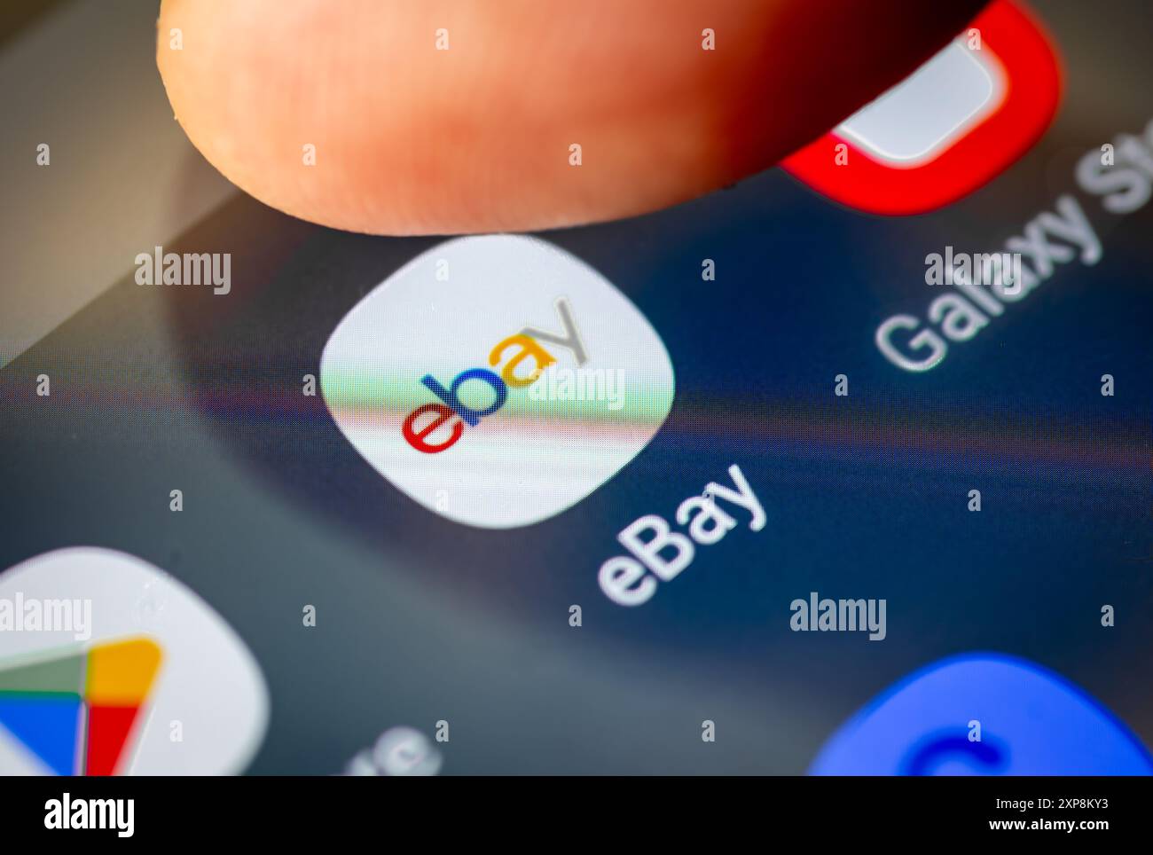 London. UK- 07.28.2024. The American multinational e-commerce app Ebay on the screen of a cellphone with a finger going forward to open the applicatio Stock Photo