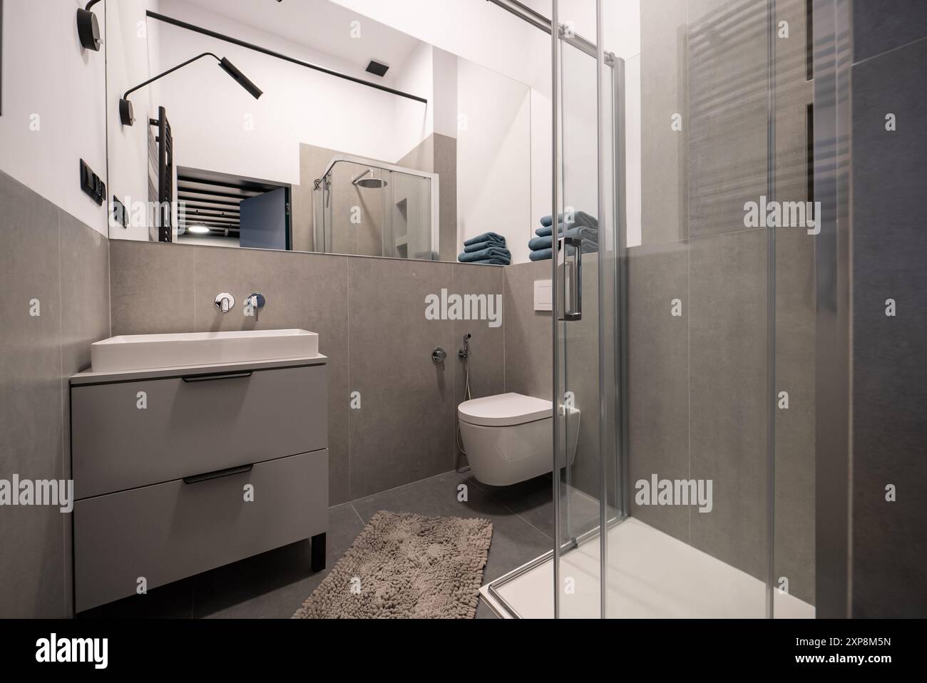 Interior of a modern bathroom featuring sleek tile walls and concrete ...
