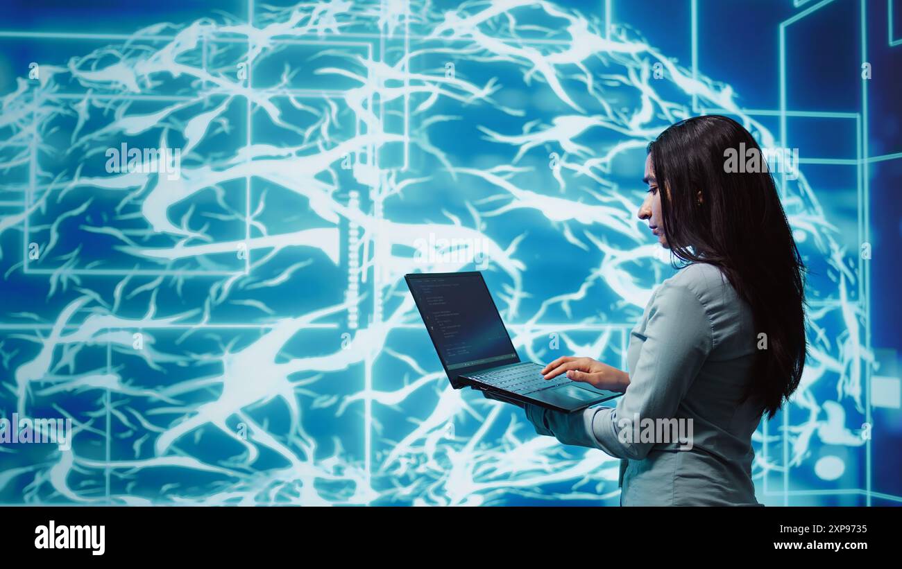 Computer scientist working on laptop, programming artificial intelligence computing simulating human brain. Woman using notebook, developing AI machine learning algorithms, camera B Stock Photo