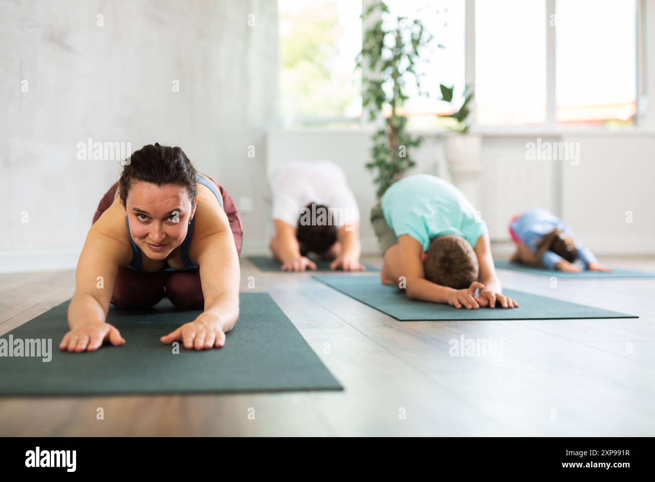 Positive middle-aged woman practicing child's pose of yoga with her ...