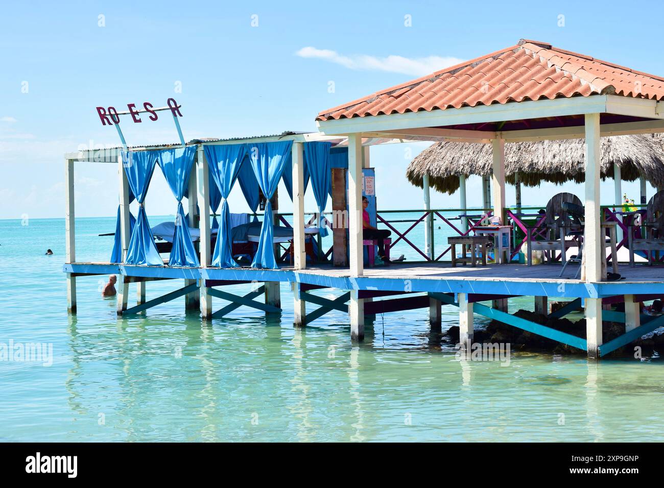 A shaded pier with seats and blue drapes on a sunny day at Secret Beach, San Pedro, Belize. Stock Photo