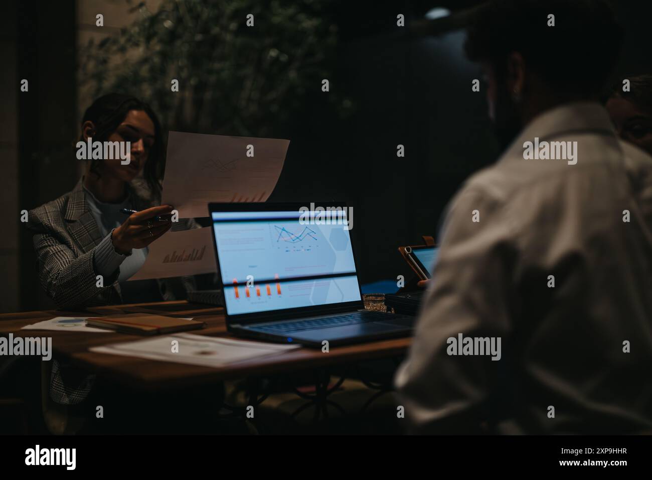 Business meeting with team analyzing charts and graphs in dark office ...