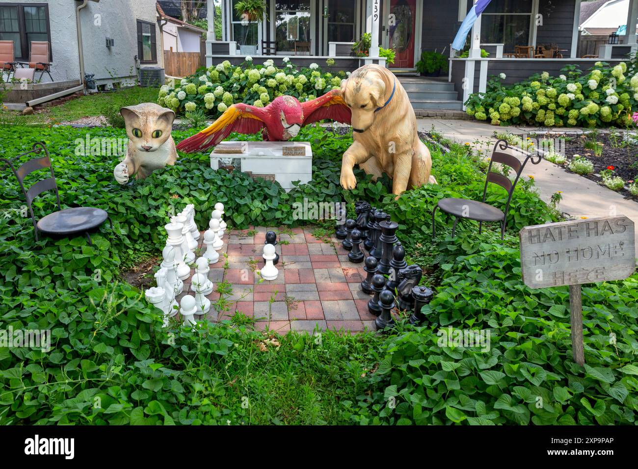 An anthropomorphic scene depicting animals - a cat, parrot, and dog playing chess outdoors in south Minneapolis, Minnesota. Stock Photo