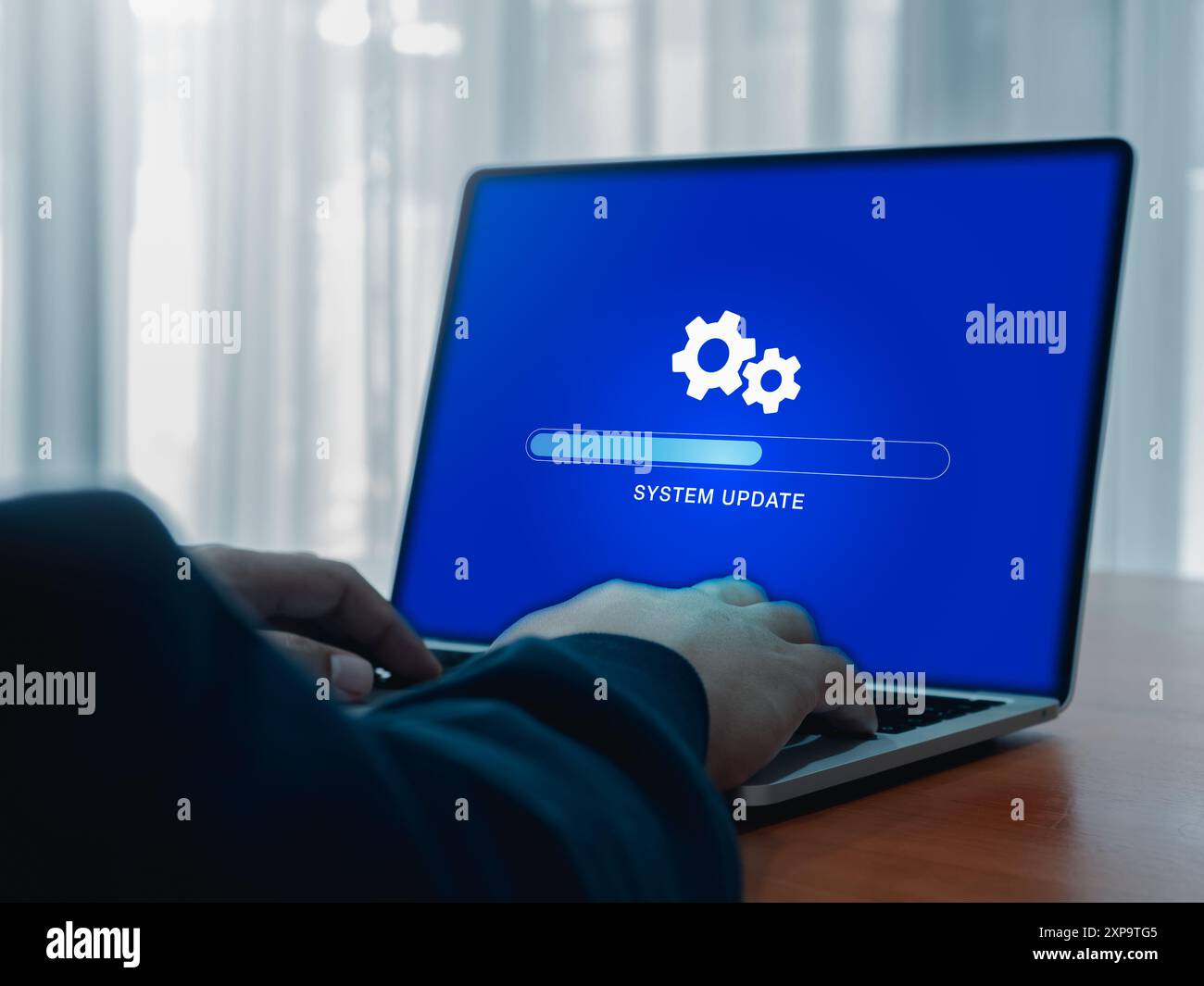 System update concept. Gear icon and updating system, loading tab bar progress operating on blue screen while businessman work with laptop computer fo Stock Photo