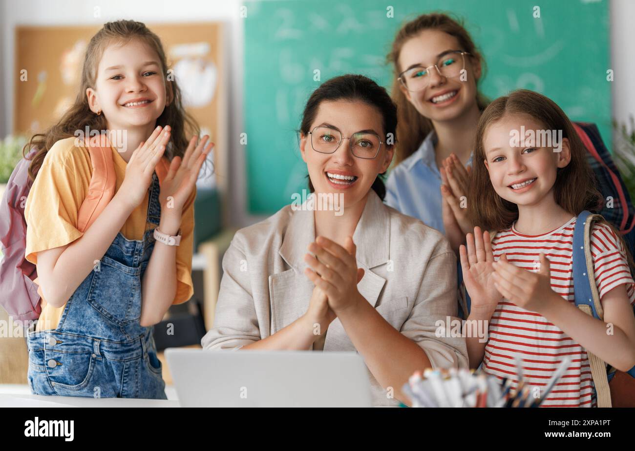 Happy kids and teacher at school. Woman and children are working in the ...