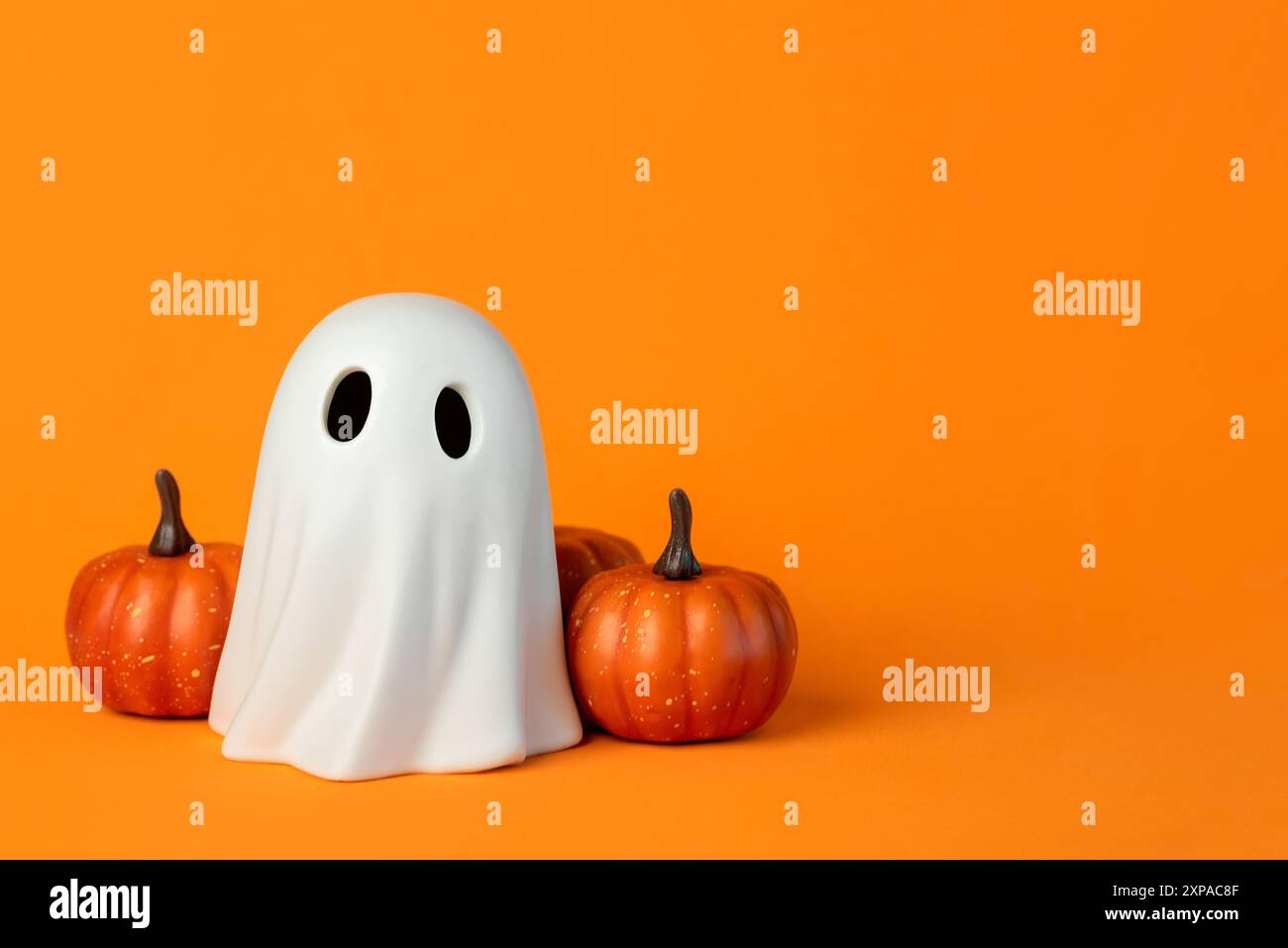 Funny Halloween ghost and Halloween pumpkins with space for text over orange background. Halloween concept background Stock Photo