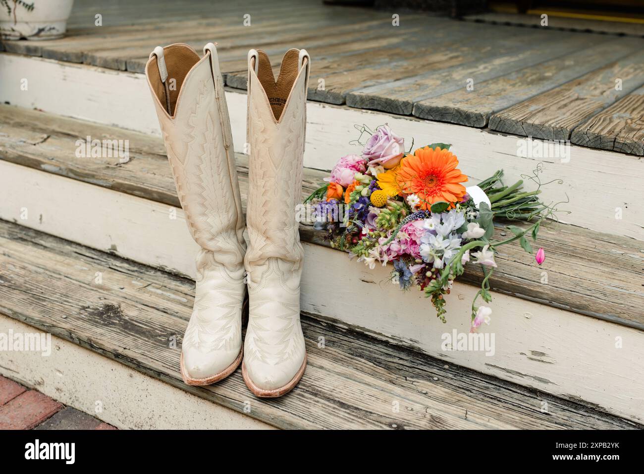 White bridal boots and colorful bouquet on wooden steps. Stock Photo