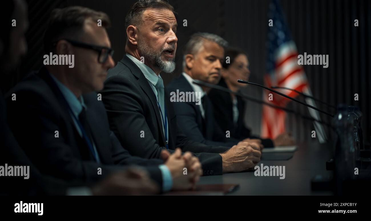 Caucasian Male Organization Representative Speaking at Economic Forum. Head Of USA Delegation Delivering Speech at International Political Summit Press Conference. Diverse Delegates Listening. Stock Photo