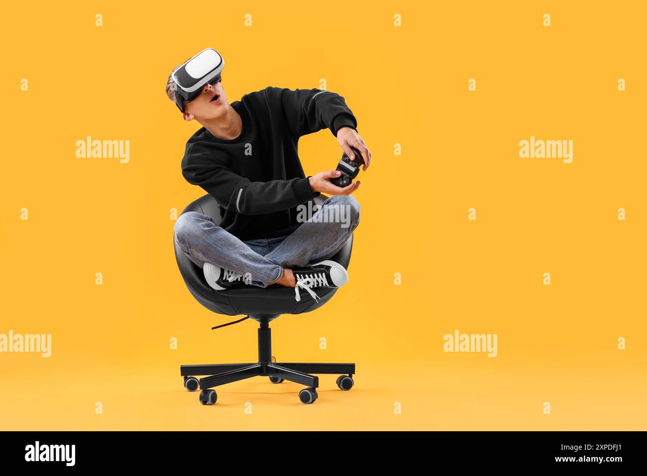 Emotional young man with virtual reality headset and controller sitting ...