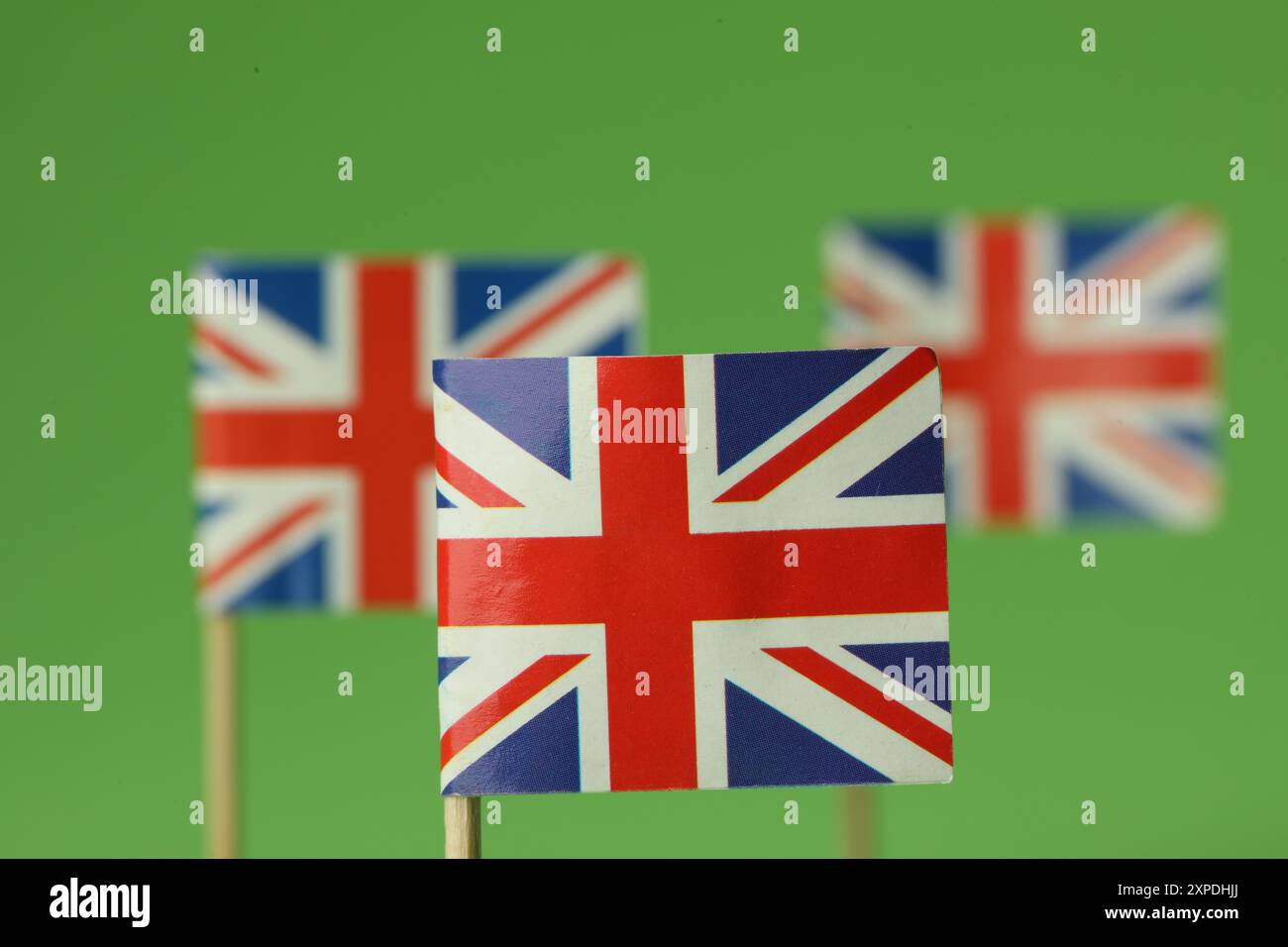 Small paper flags of United Kingdom on green background, selective ...