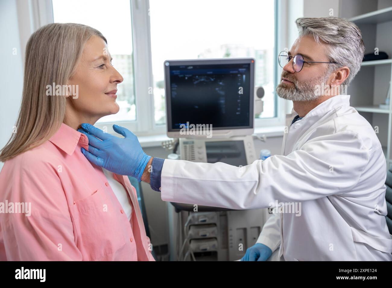 Palping Male doctor palping female patient throat and looking focused Stock ...