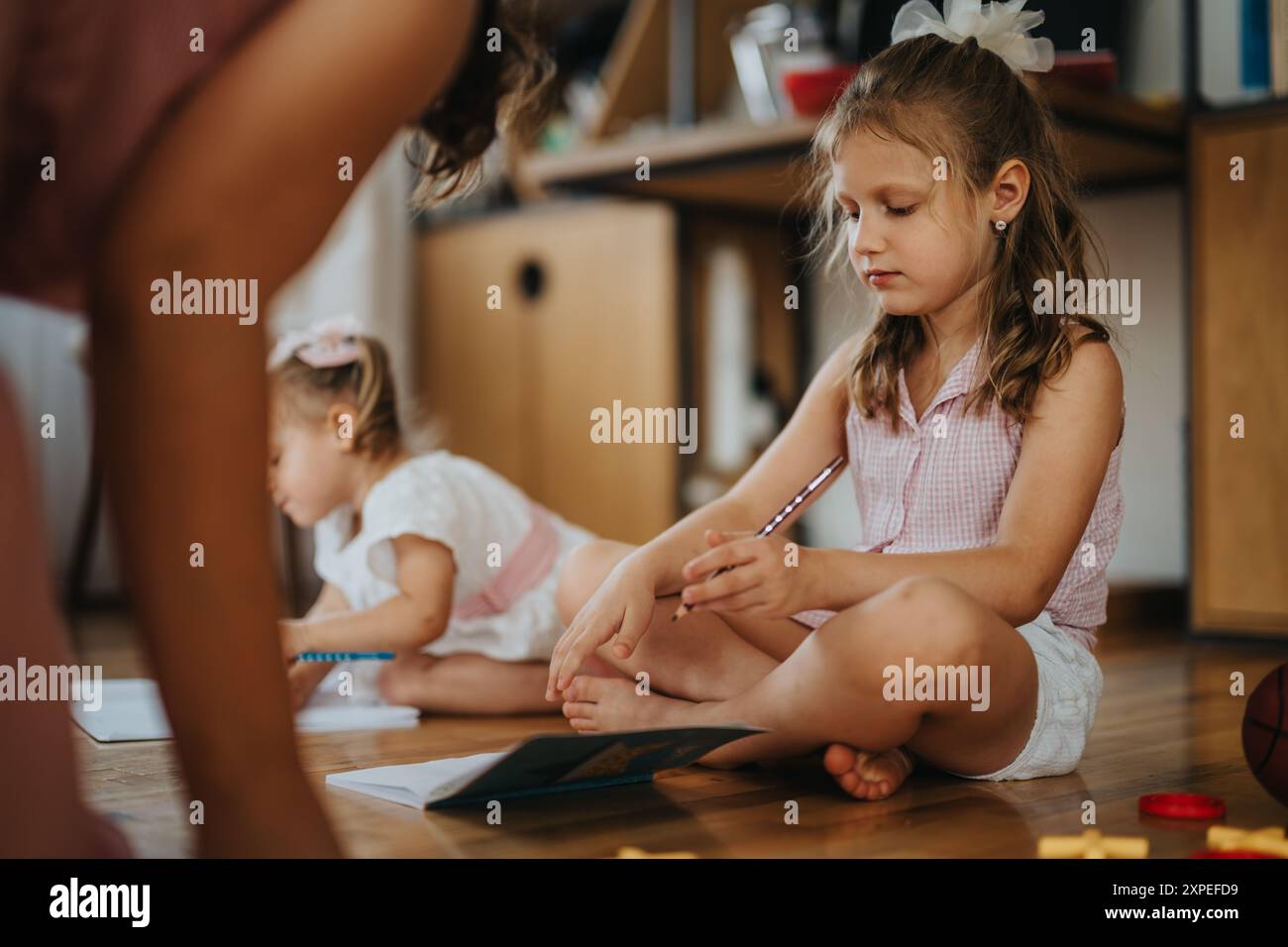 Little girl engaged in coloring activities with her sister at home ...