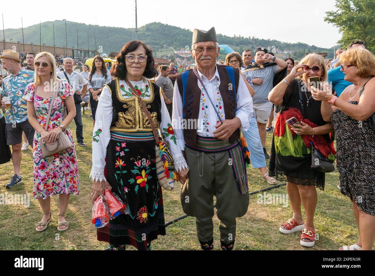 Guca. 4th Aug, 2024. A couple in Serbian traditional folk costumes are pictured at the venue of a brass orchestra competition during the 63rd Guca Trumpet Festival in the village of Guca, Serbia on Aug. 4, 2024. TO GO WITH 'Feature: Traditional Serbian music and cuisine on show at Guca trumpet festival ' Credit: Nemanja Cabric/Xinhua/Alamy Live News Stock Photo