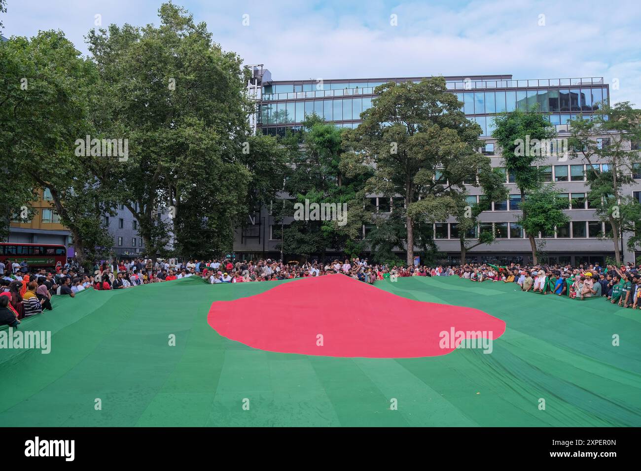 London, UK, 5th August, 2024. The British-Bangladeshi community celebrated the news of Prime Minister Sheikh Hasina's resignation, in Altab Ali Park,  East London. Crowds surround a giant national flag of Bangladesh. Student protests in the South Asian country over civil service job quotas for those who participated in the 1971 Liberation War, led to increasing disatisfaction of Ms. Hasina's leadership. Credit: Eleventh Hour Photography/Alamy Live News Stock Photo