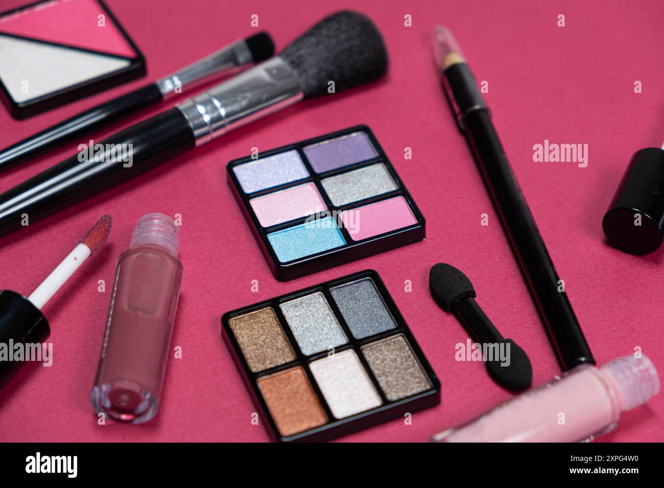 Various decorative cosmetics and brushes on a pink background. Stock Photo