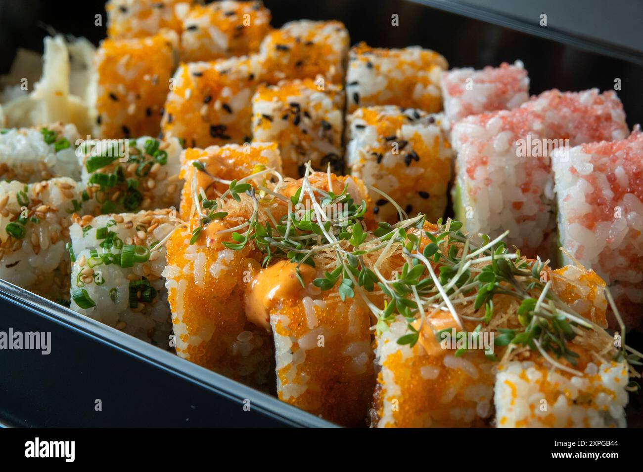 Delicious sushi rolls side by side in a black tray. Close up image with selective focus and shallow depth of field. Stock Photo