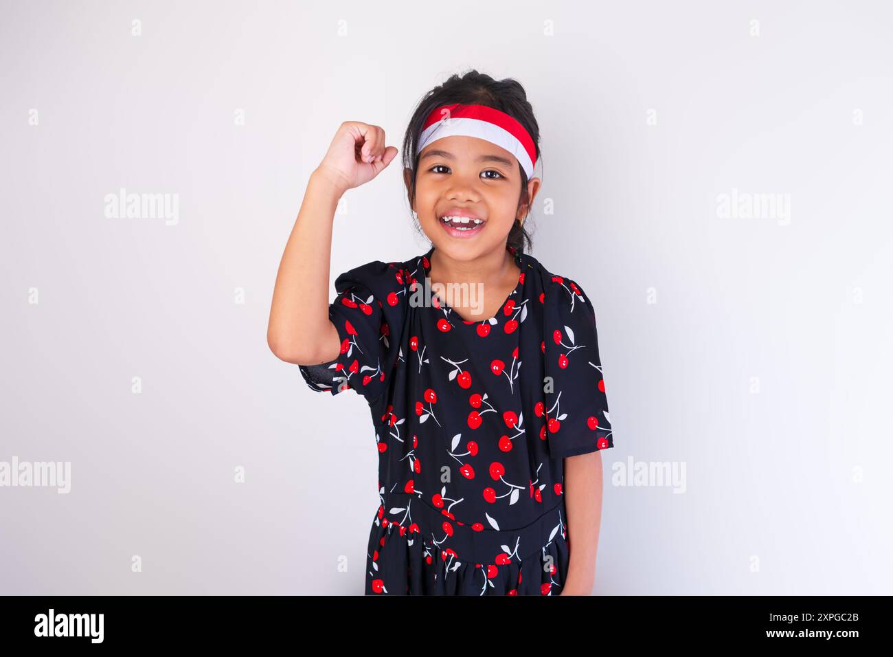 A beautiful girl wearing an Indonesian flag headband and a black dress posing with the theme of Indonesian Independence Day Stock Photo