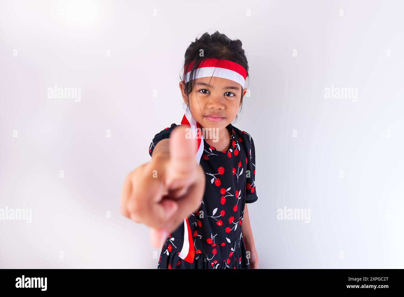 A beautiful girl wearing an Indonesian flag headband and a black dress posing with the theme of Indonesian Independence Day Stock Photo