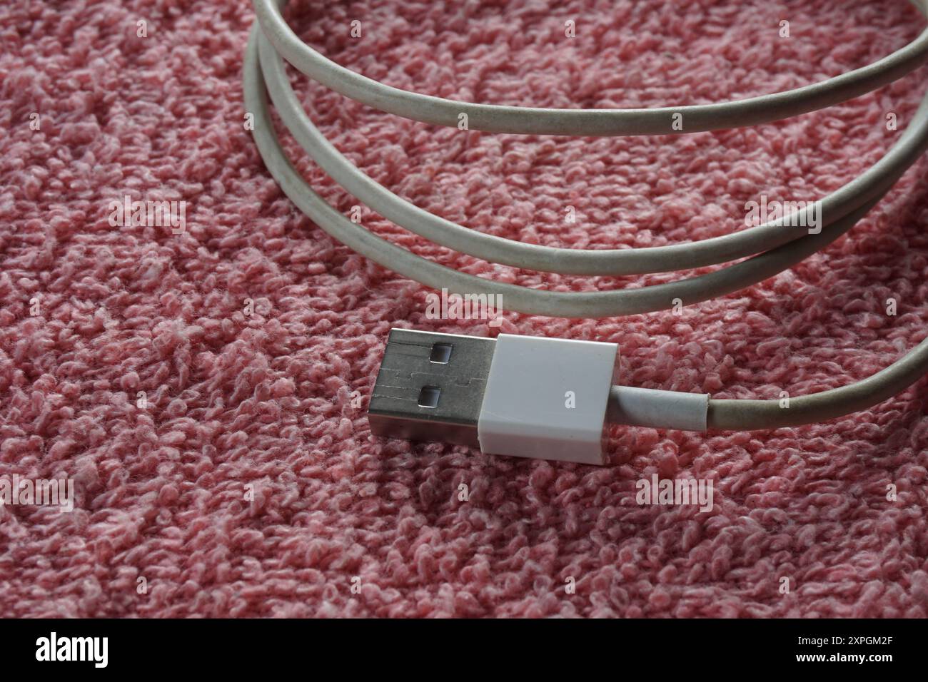 Closeup of white smartphone cable on red background. Usb-A smartphone cable. Stock Photo