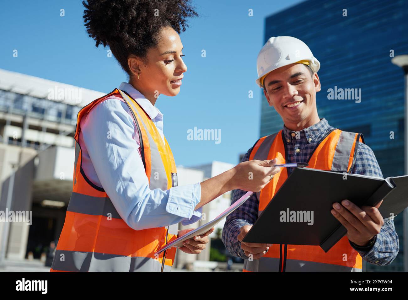 Diverse Construction Workers Collaborating on Outdoor Building Project Stock Photo