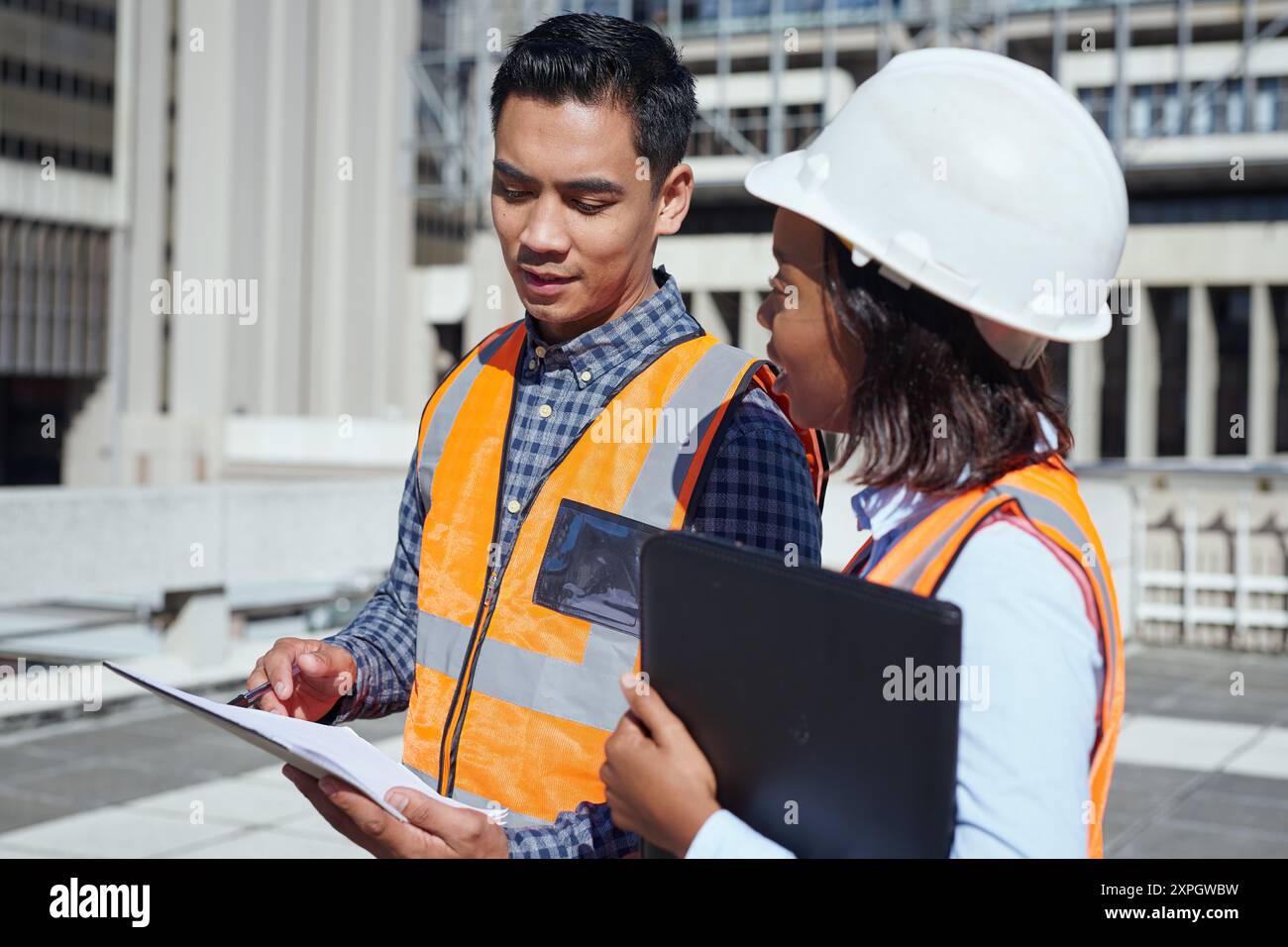 Diverse Engineers Discussing Blueprint Plans at Construction Site Stock Photo