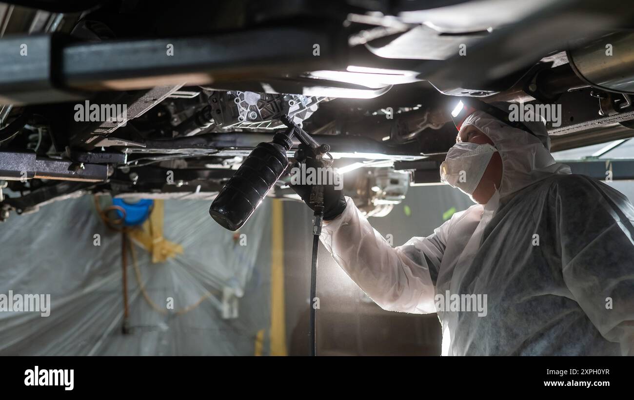 The master sprays an anti-corrosion compound on the bottom of the car ...