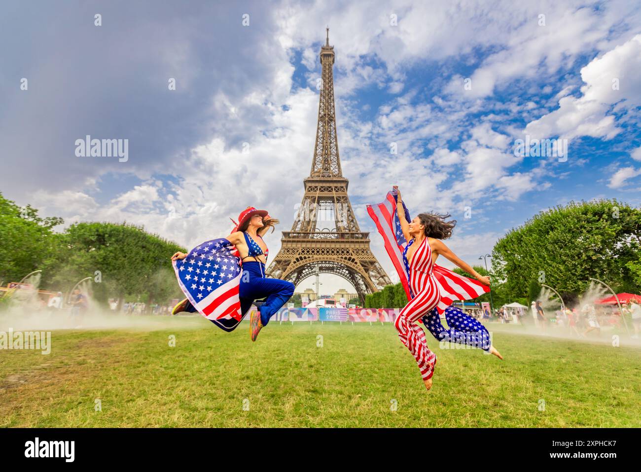 Patriotic American Woman jumping and cheering for Team USA and the Paris 2024 Olympics in front of the Eiffel Tower, Paris, France, Europe Stock Photo
