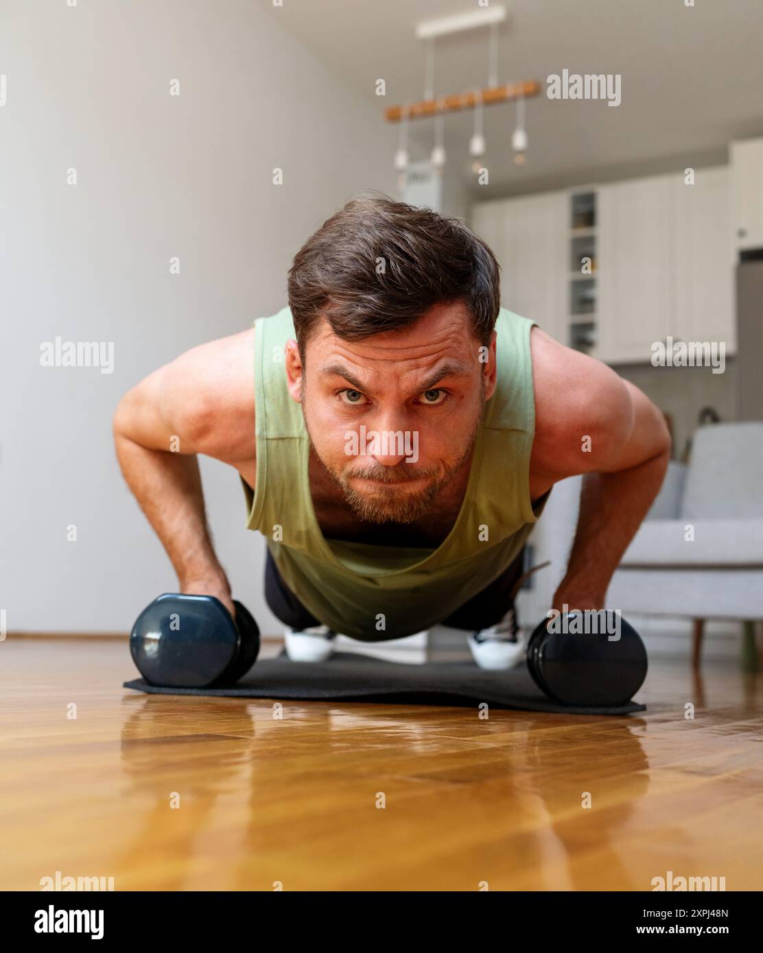 man doing push-ups with dumbbells at home Stock Photo