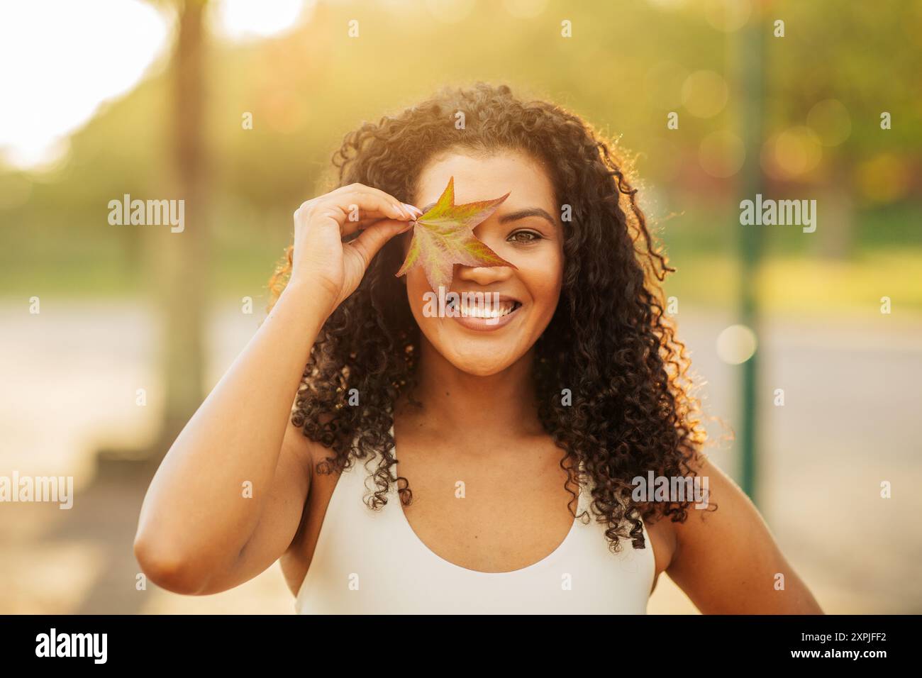 Young Woman Joyfully Holding Autumn Leaf Near Her Face Stock Photo - Alamy