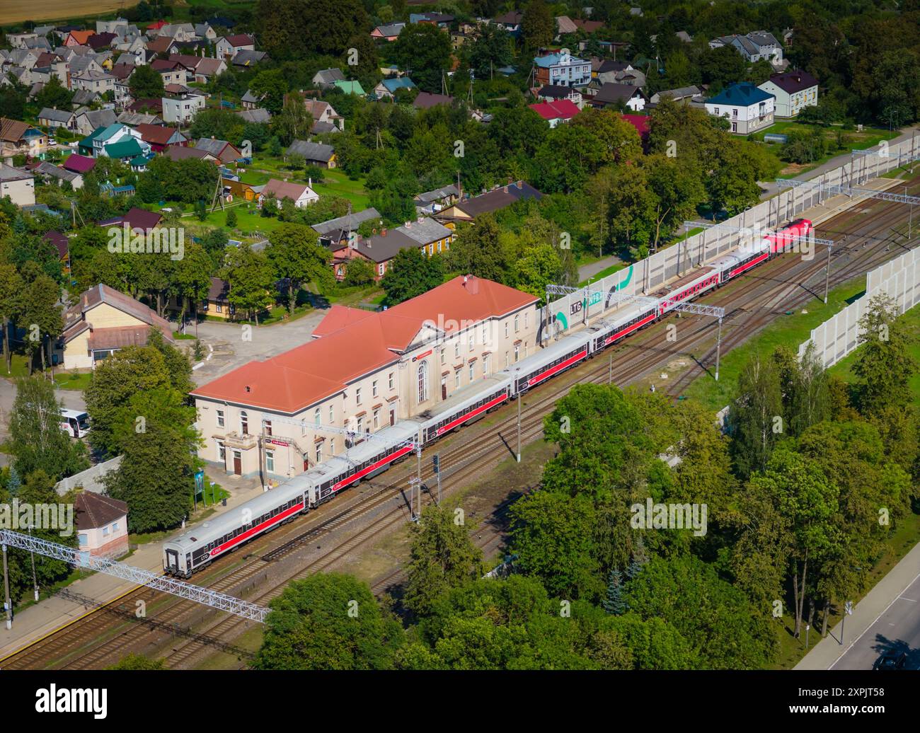 Railroad station in Kaisiadorys, Lithuania. Aerial drone view photo of passenger and freight train station with train passing by Stock Photo