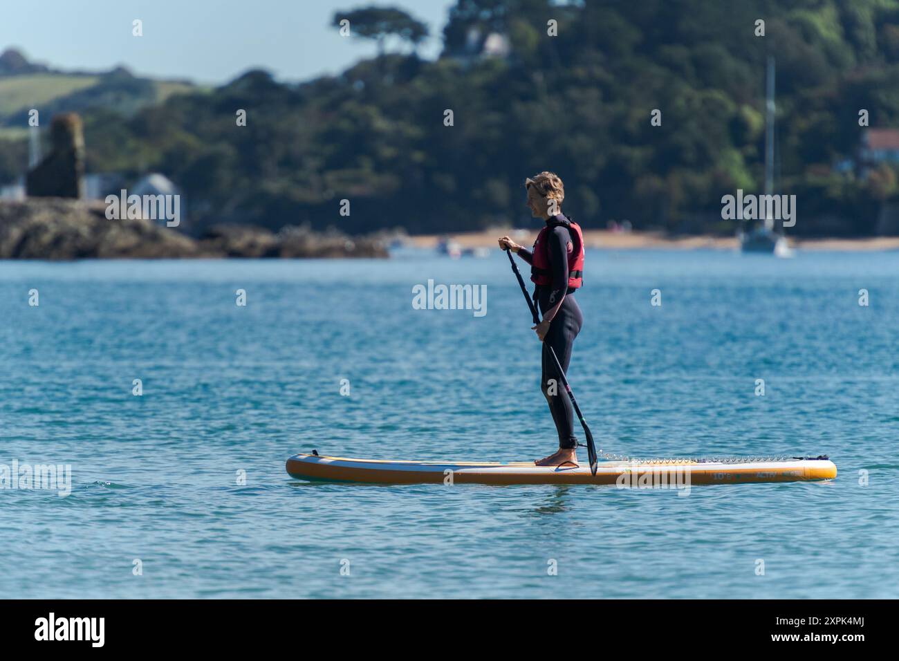 Paddle board (SUP) lesson from South Sands with Fort Charles castle ruin and East Portlemouth beach in soft-focus in background, on warm summers day Stock Photo