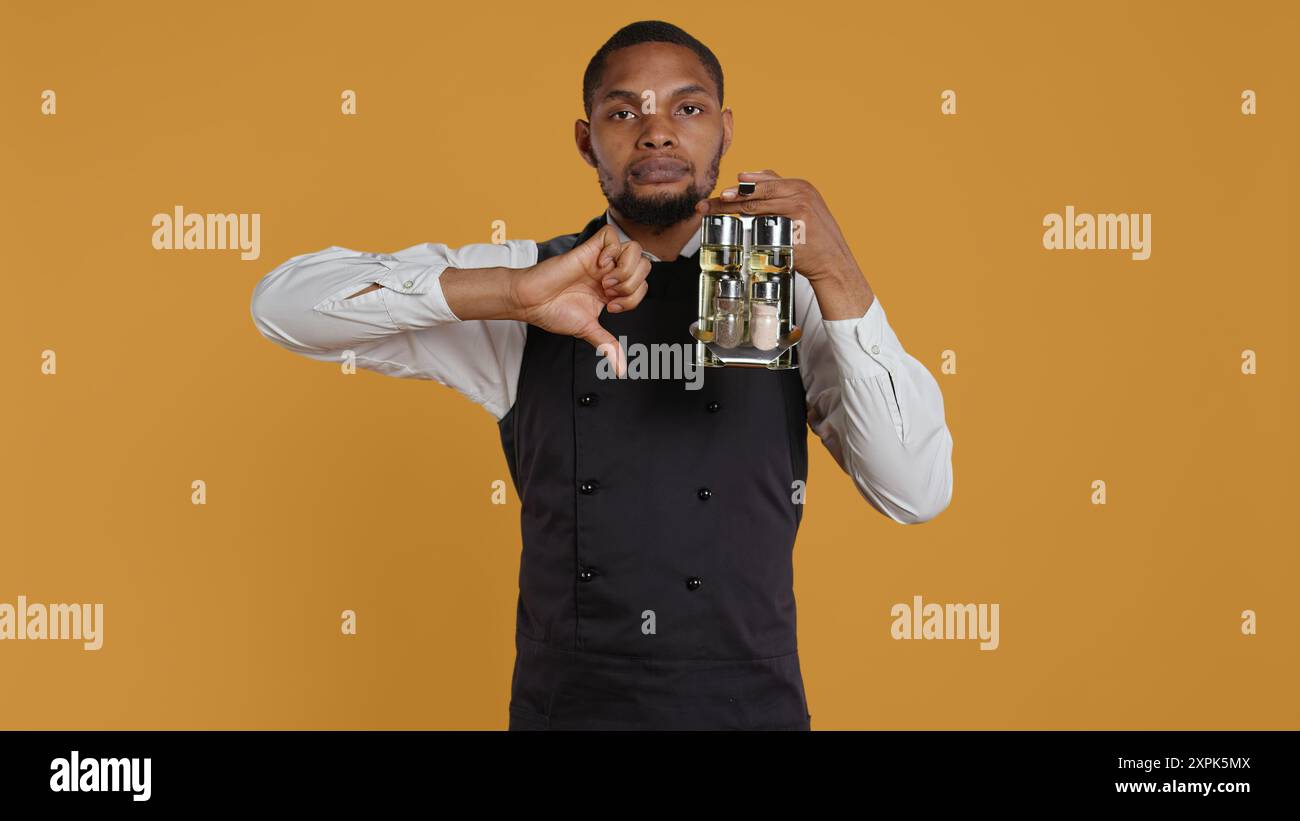 Restaurant staff giving a thumbs down sign against yellow background ...