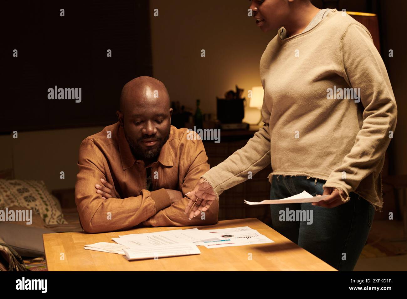 Cropped shot of annoyed wife showing overdue bills and eviction notice to upset husband while standing by table in front of him Stock Photo