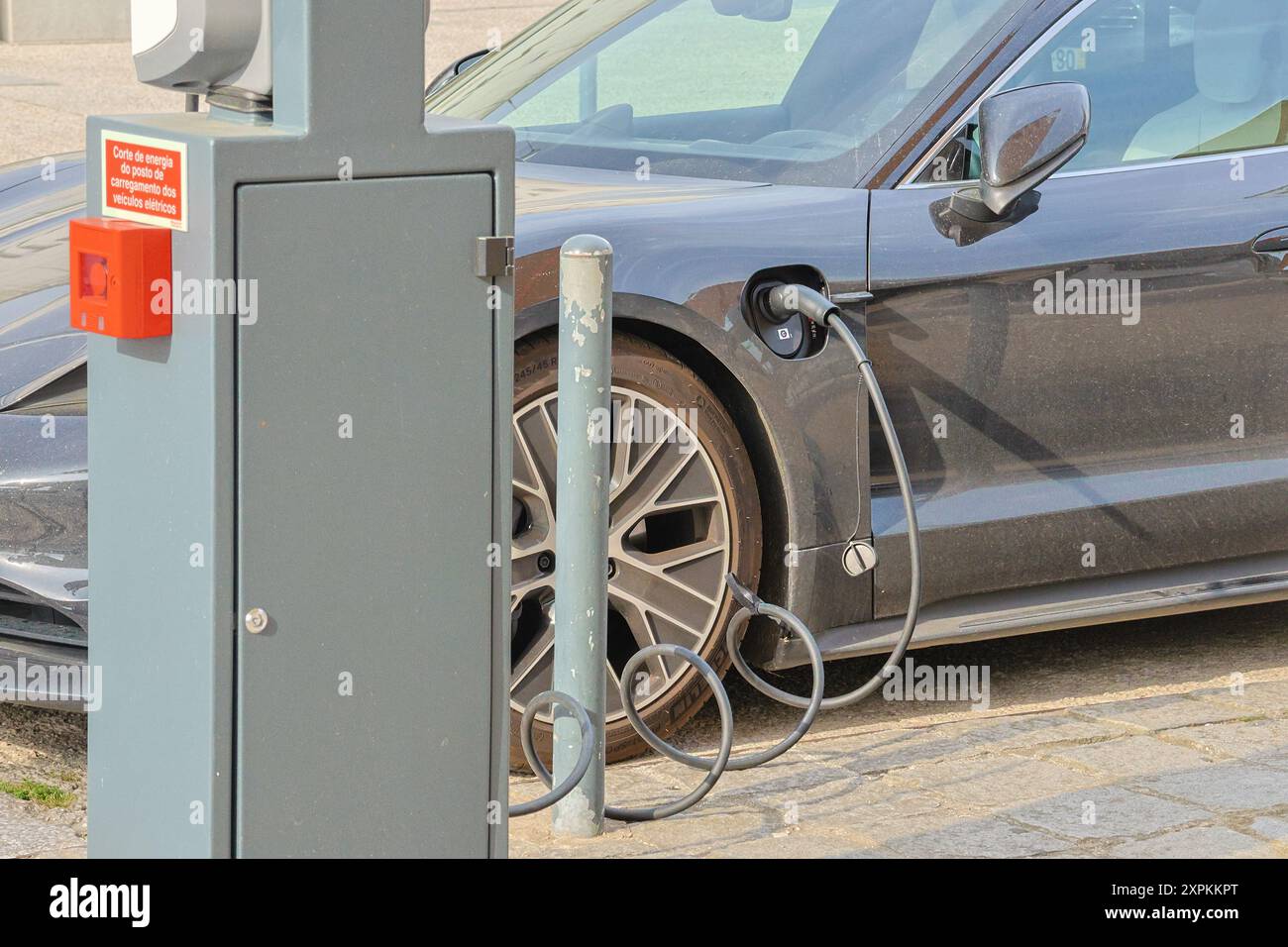 Modern electric car plugged in and charging at an urban charging point ...