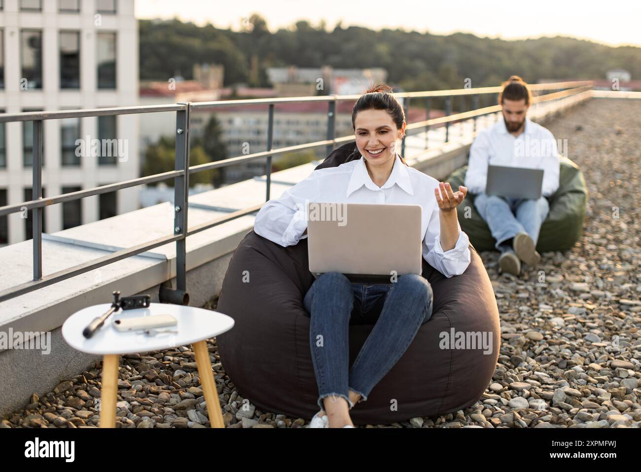 Colleagues working outdoors on rooftop with laptops Stock Photo