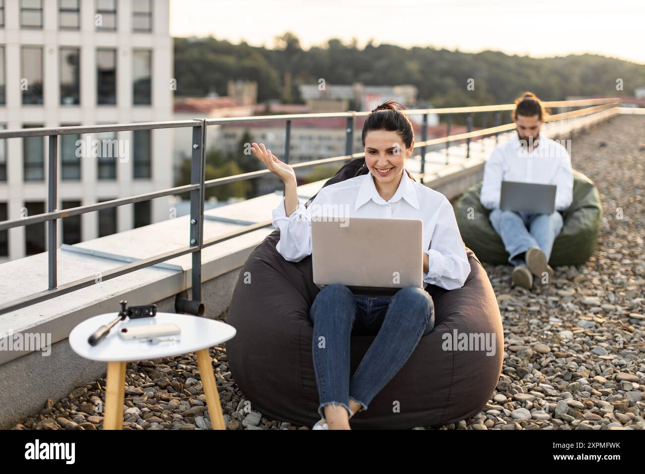 Young professionals working on laptops on rooftop terrace Stock Photo