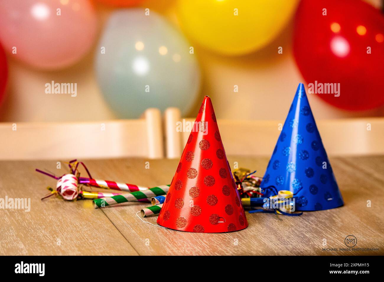 The colorful party hats and blowers on a wooden table with balloons in ...